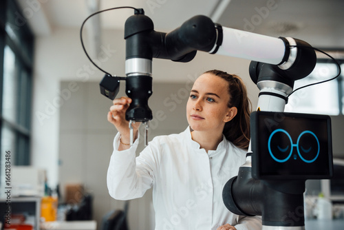 Technician working with robotic arm in laboratory with AI support