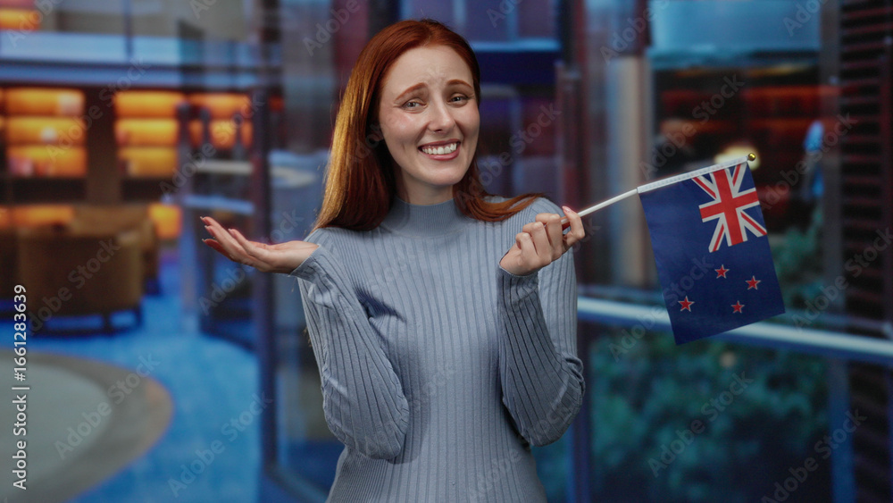 Woman holding new zealand flag indoors in hotel smiling with happiness showcasing patriotism and joy in modern setting with elegant redheaded hair and stylish sweater Woman holding new zealand flag indoors in hotel smiling with happiness showcasing patriotism and joy in modern setting with elegant redheaded hair and stylish sweater