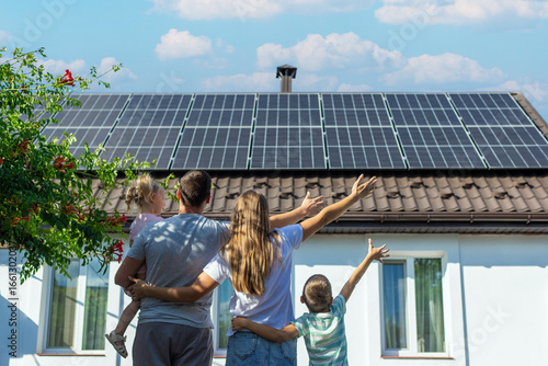 happy family on the background of a house with solar panels on the roof. Selective focus