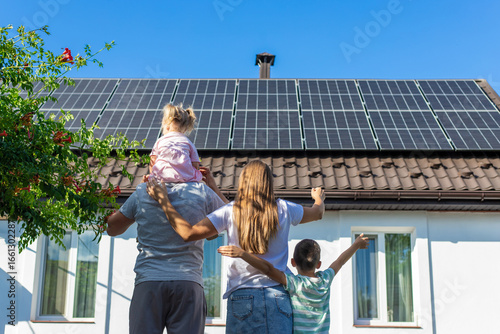 happy family on the background of a house with solar panels on the roof. Selective focus