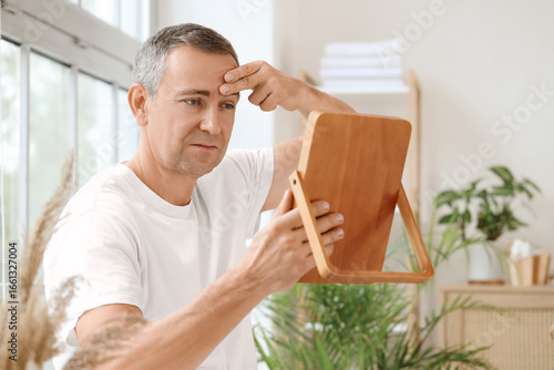 Mature man with mirror doin...