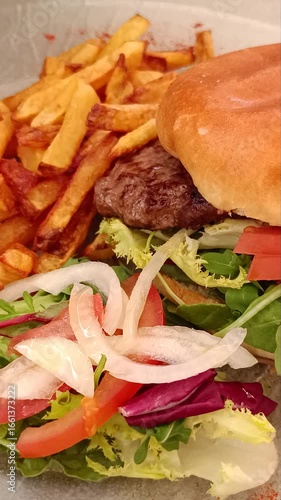 Grand hamburger savoureux avec frites et salade.