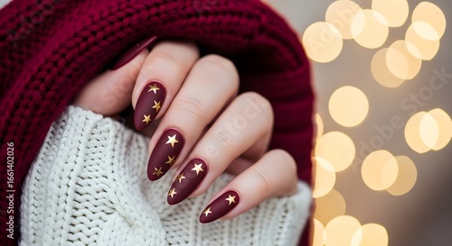 Woman's hand with dark red manicure and gold star nail art
