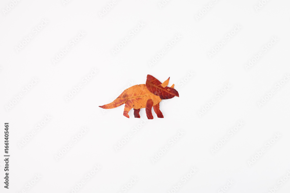 Obraz premium Triceratops made of autumn leaves symbolizing creativity, eco design, and nature art, ideal for education, children publishing, seasonal marketing, environmental campaigns, and DIY brands,
