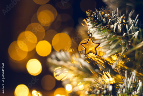 Christmas tree toy in the form of a golden star  on a branch. Christmas and New Year decoration, flashing garland, illuminated lamps. Christmas mood background.