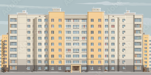 Symmetrical facade of a beige and yellow multi-story panel apartment building, a typical Eastern European residential block.