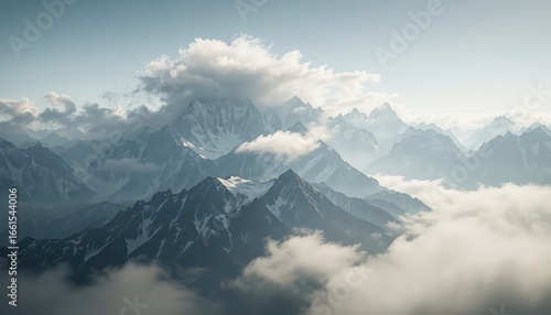 Serene vista of jagged mountain peaks partially obscured by ethereal clouds casting shadows on the snowy slopes under a soft pale sky