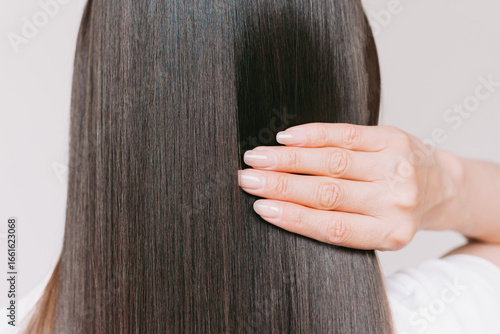 Young caucasian beautiful brunette woman with smooth shiny brown and straight long hair after keratin straightening.