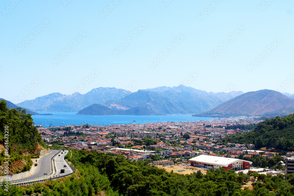 Fototapeta premium Scenic coastal Marmaris town nestled between mountains and the sea under a clear blue sky. Mugla,Turkey.