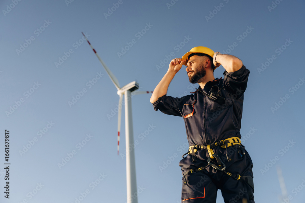 Naklejka premium Break time, standing. Engineer in field checking on wind turbine production