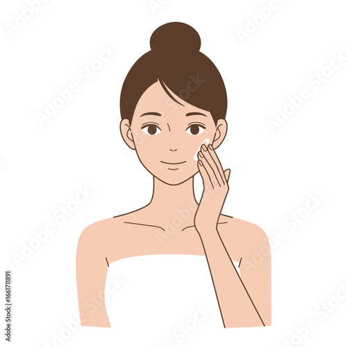 A serene young woman with a neat bun applies a luxurious facial cream to her cheek, embodying a gentle and effective skincare routine for healthy, glowing skin.