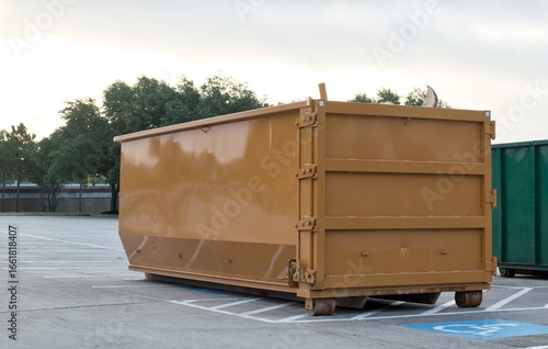 Dumpster rental industrial bin in commercial parking lot site brown trash removal skip.