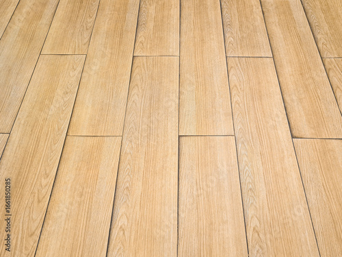 Background of a textured wood-patterned floor. Rough surface of SPC (Stone Plastic Composite) vinyl floor tiles with wood grain pattern. Material is made from natural stone powder combined with resin.