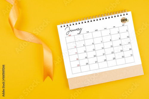January 2026 desk calendar with yellow ribbon on yellow color background, Flat lay.