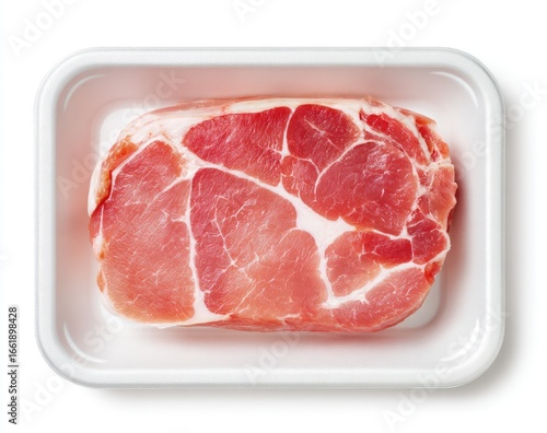A single, raw pork chop, marbled with fat, rests in a white plastic tray against a stark white background, viewed from directly above