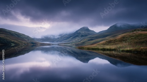 Mountain reflection in loch landscape with fog creating a moody atmospheric scene