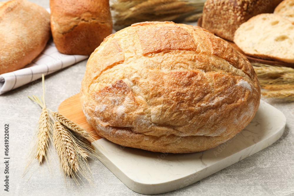 Naklejka premium Different types of bread and wheat spikes on grey table, closeup