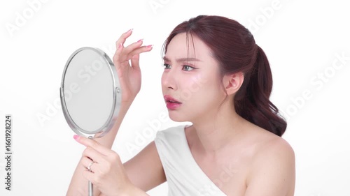 Young woman looking at her skin in the mirror with a concerned expression, assessing her complexion representing concerns like skincare, skin problems, or beauty routines.