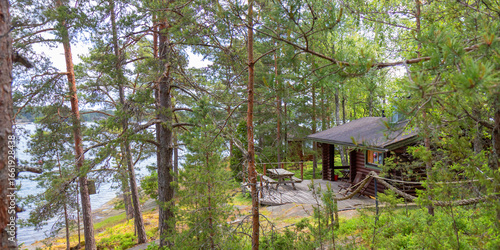 Terrace of a Finnish summer sauna house with chairs and table, overlooking pine forest and Baltic Sea archipelago. Peaceful retreat on island, traditional lifestyle and relaxation after sauna