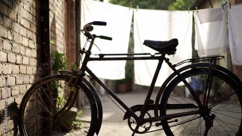 A vintage bicycle against a brick wall with clothesline view
