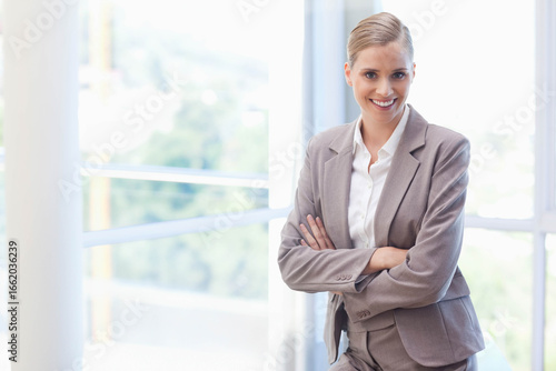 Female executive standing by glass windows with metal balcony railing in office lobby  copy space