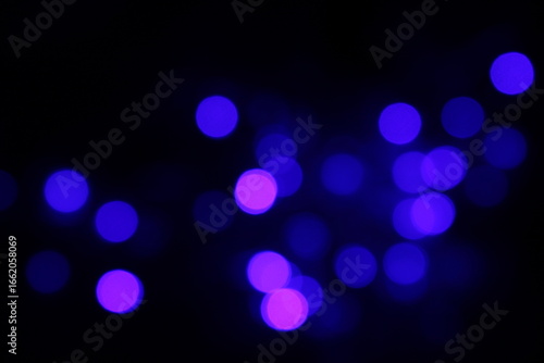 Christmas lights in bokeh. Outside in December. Snow and blue bokeh on a black background, bokeh abstract background, modern technological abstract background. Blue Christmas background, Xmas bokeh 

