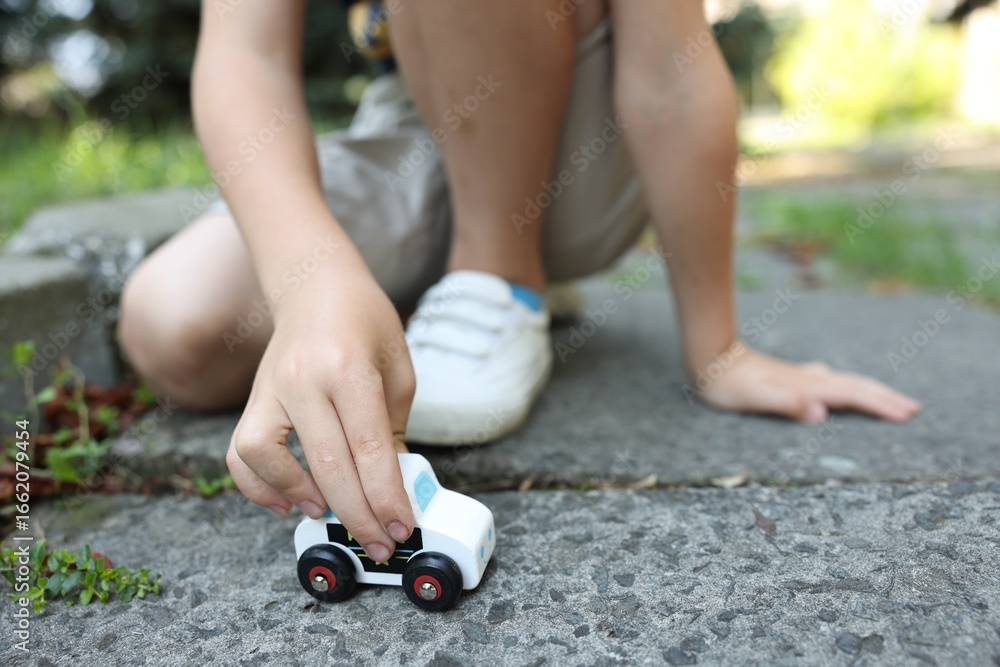 Naklejka premium Little boy playing with toy car outdoors, closeup