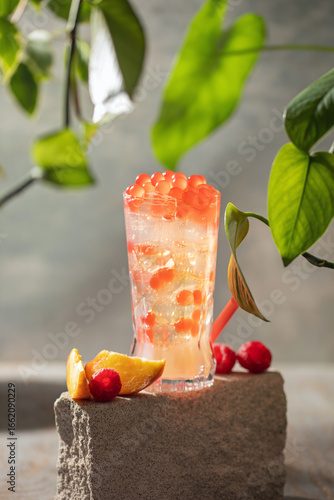 Cold iced peach raspberry bubble tea with juice balls in glass