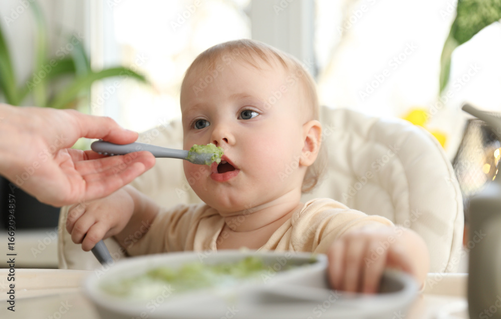 Mom's hand feeds the little baby with a spoon Mom's hand feeds the little baby with a spoon