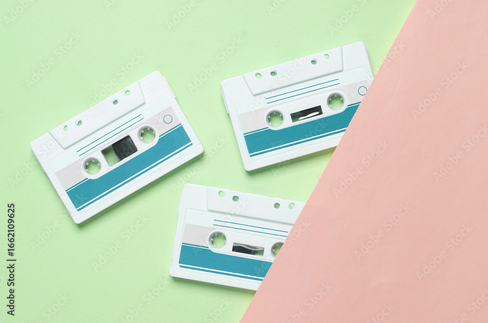 Fototapeta premium Retro 80s audio cassettes on blue pink background. Music concept, vintage technology. Top view