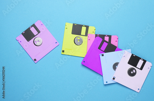 Many colored floppy disks on blue background. Computer technology 80s. Top view.