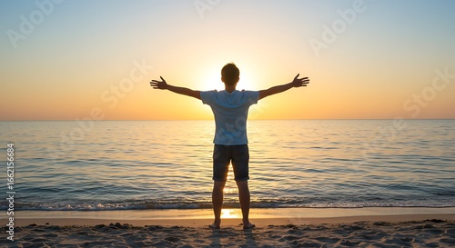 Young man arms outstretched by the sea at sunrise enjoying freedom and life, people travel wellbeing concept