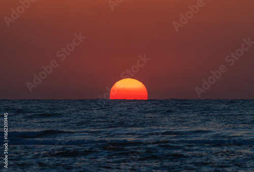 Fototapeta Naklejka Na Ścianę i Meble -  Beautiful landscape with sunrise over the sea. The sun rises from the sea water