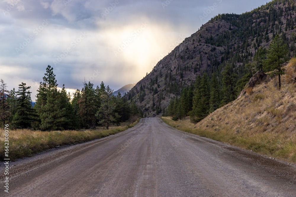 Fototapeta premium Dirt Road Through Mountains and Trees at Sunrise in BC, Canada