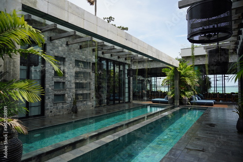 Obraz na plátně Modern tropical villa with a swimming pool and stone walls, surrounded by lush greenery