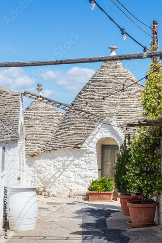 White ancient stone house with conical roof in the unique village Alberobello, Italy.