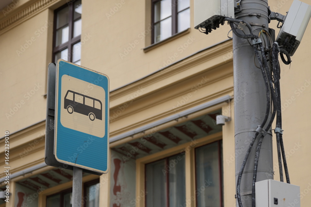 Obraz premium Close-up of a blue bus stop sign on a city street with building in the background 