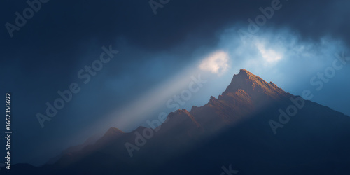slanted light shining through broken clouds on mountain ridge