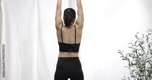 A woman practices a stretching exercise for wellness and healthy living in her home, Healthy habits for a balanced life.