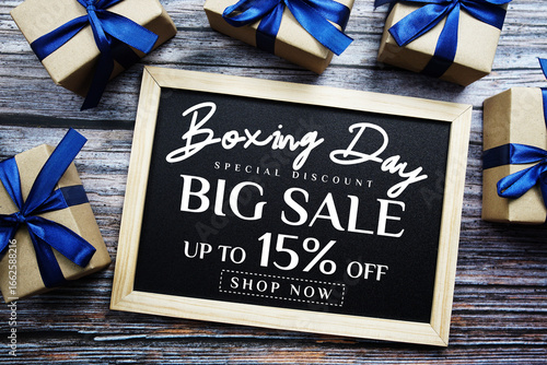 Boxing Day Big Sale 15% Off text on blackboard with present gifts on wooden background