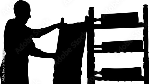 Silhouette of person placing a canvas next to a shelf with rolling pins in a well lit environment