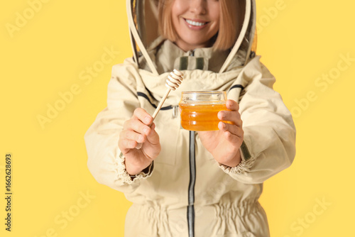 Female beekeeper with jar o...
