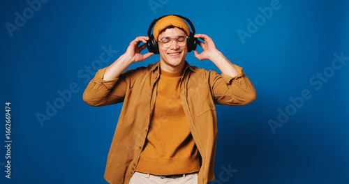 Fototapeta Studio, dancing and man with headphones, music or listening to audio with tech, streaming or online