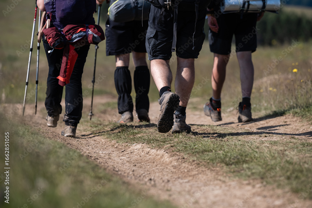 Fototapeta premium Hikers walking on dirt trail in countryside
