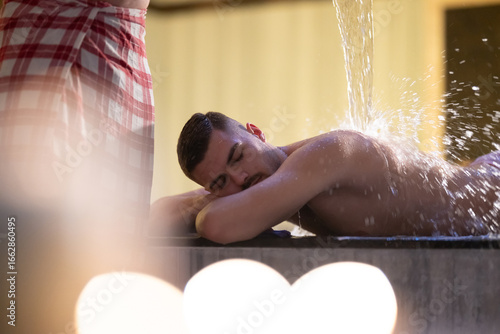 Fotografie Man receiving water therapy inside a traditional Turkish hammam with ornate details