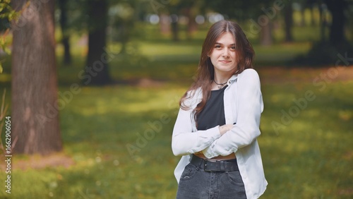 Fotografie Young georgian woman standing with crossed arms, radiating confidence amid verda