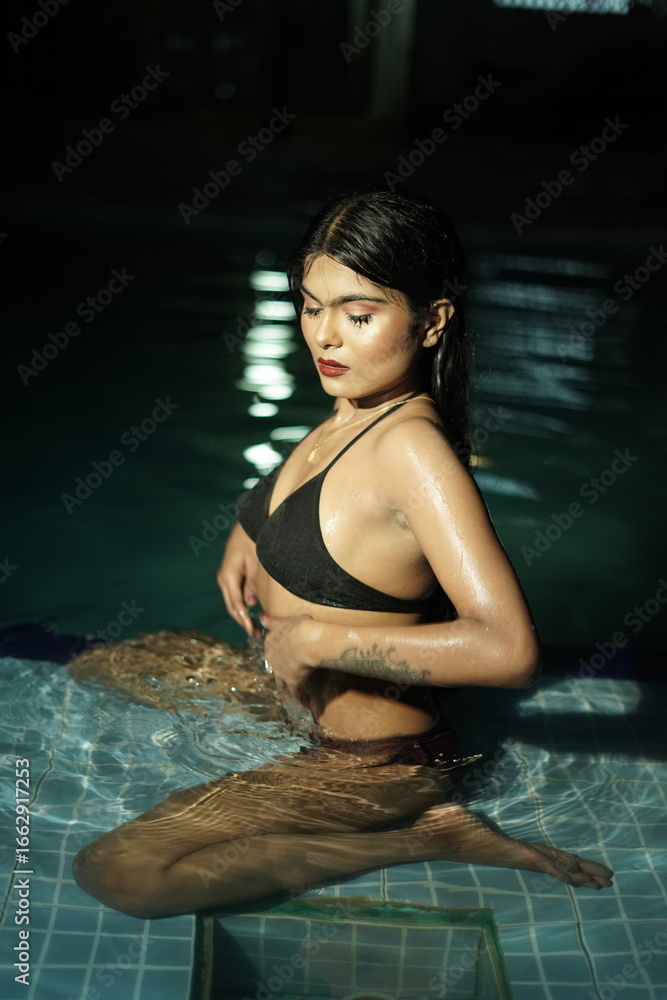 Fototapeta premium Woman Sitting in Swimming Pool with Upper Body Above Water in Bikini Portrait