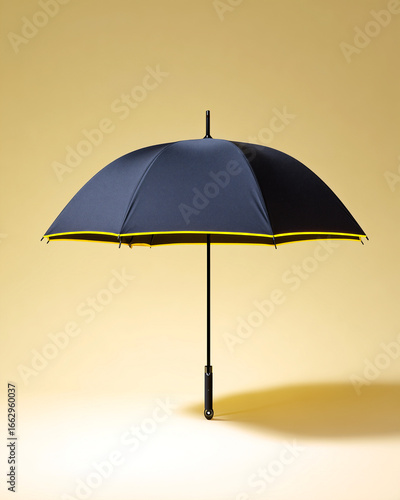 Modern black umbrella with yellow trim standing open on a yellow background, minimalist studio shot with stylish design