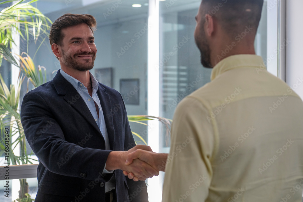 Fototapeta premium Two businessmen shaking hands in modern office, establishing a successful partnership