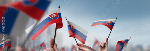 Photography Slovakia flags in their hands on a blurred urban background